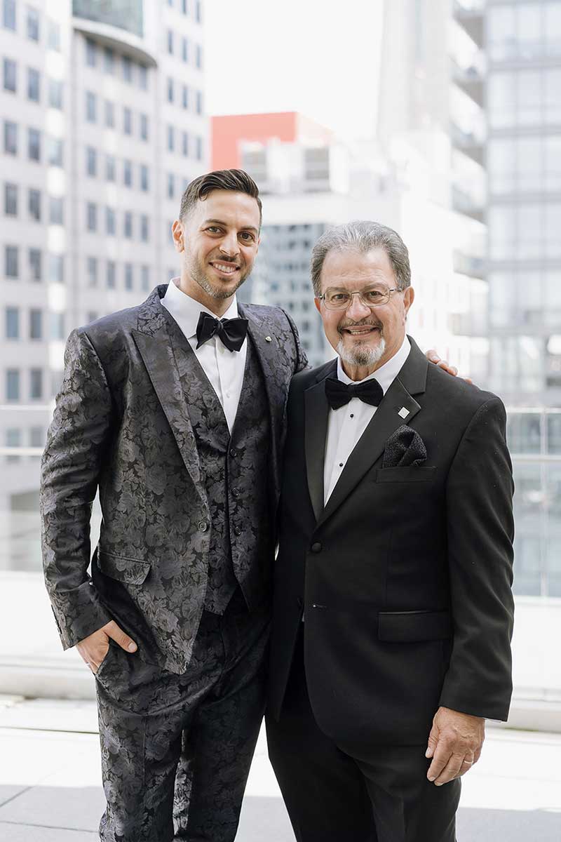 A very well-dressed young man stands next to his father on his wedding day.