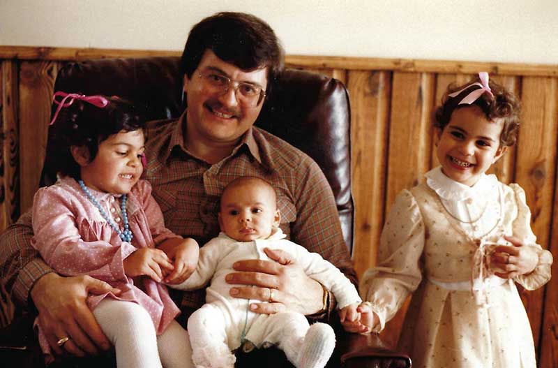 A man sits with three children in front of him.