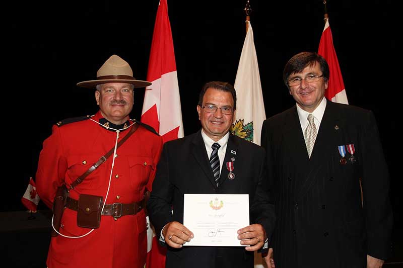 A man holds a certificate as he stands between two officials.