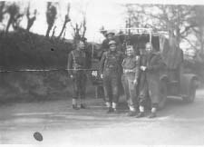 Group of soldiers standing in front of army jeep.