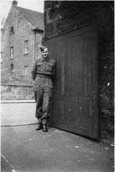Young man in uniform standing against building wall.