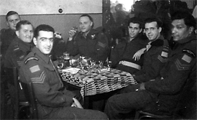 Group of young men in military uniforms, seated around a table.