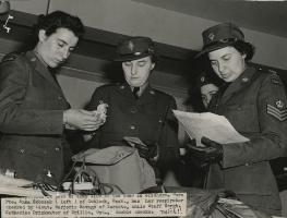 Three female officers looking in a sports bag and holding papers. 