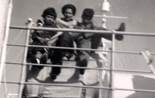 Three family members leaning against railing of ship.