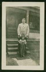 Gerald and his young daughter standing in front of the steps of his house. 