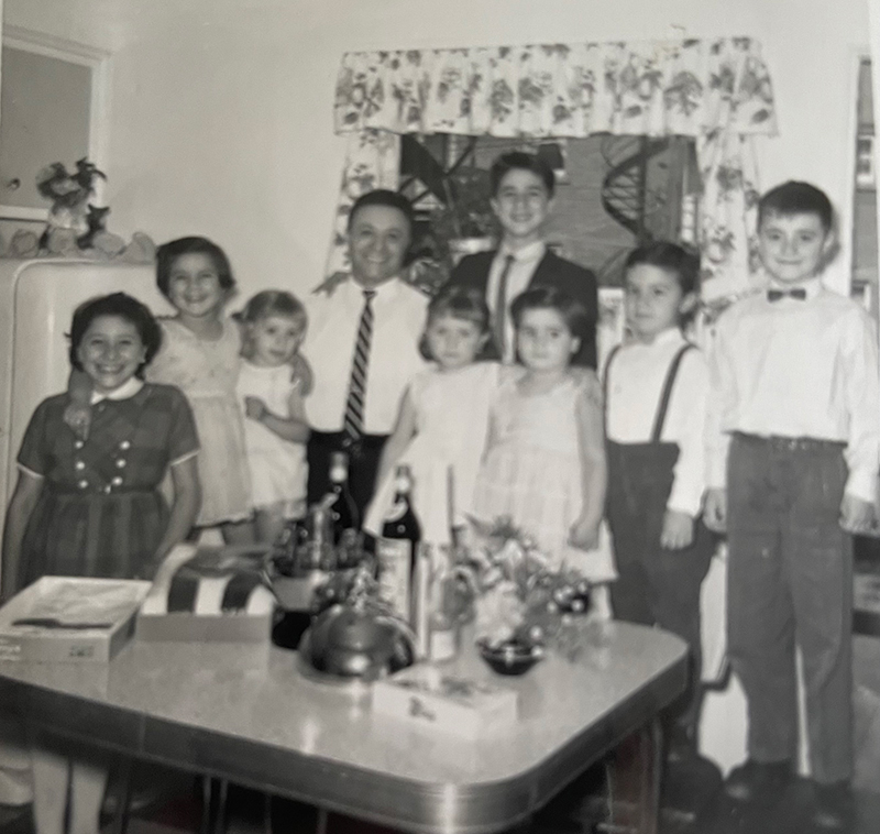 A man is surrounded by eight children, all are well-dressed.