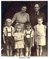 Mother and father with two boys and two girls standing in front.