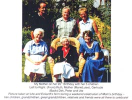 Garden photo of elderly woman in wicker chair surrounded by family.