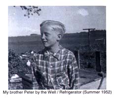Young blond boy in checkered shirt, standing in front of a well. 