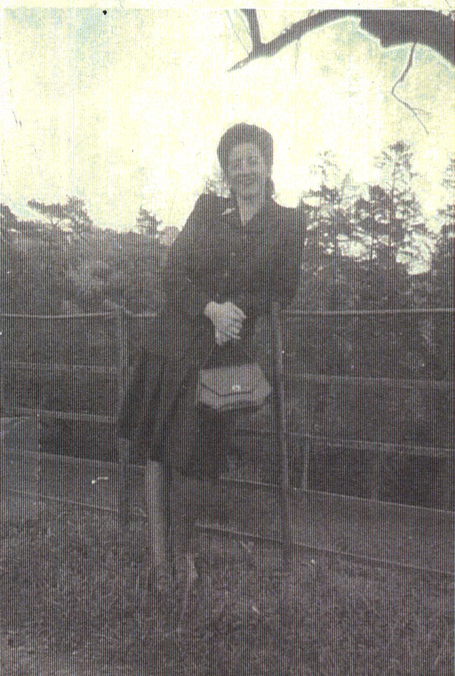 Woman leaning up against fence.