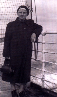 Woman in black clothing and hat, elbow on the railing of a boat.