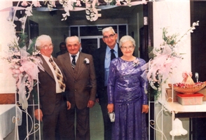Older woman in purple dress, standing with three men in costume.