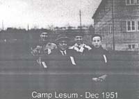 Blurry photograph showing four people standing in front of a building with the legend Camp Lesum - Dec 1951.