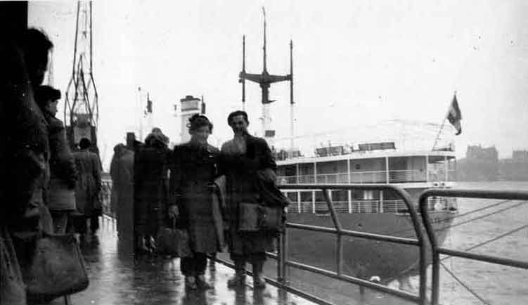 Couple is standing on the dock of the ship for photo.