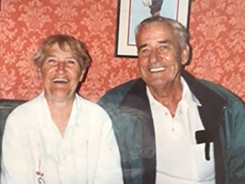 A couple are  sitting and smiling for a photo.