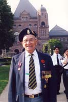 Henry as an older man with military medals on jacket and pins on beret.