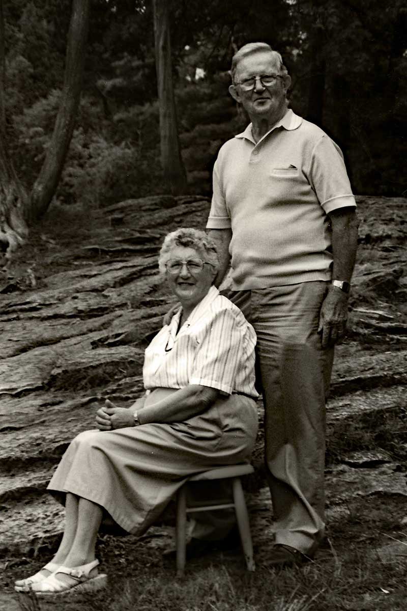 An outdoor picture with a woman seated and a man standing behind her.