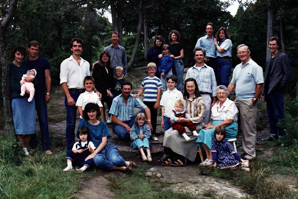 A large group of family members are seated and standing outside for a portrait.