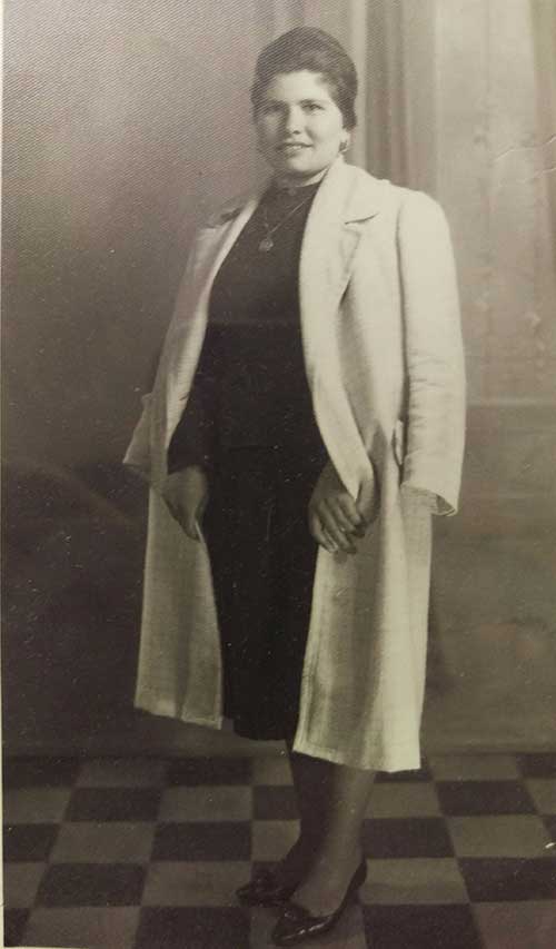 A young woman wearing a black dress with a white coat.
