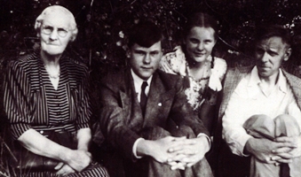 Older woman with three young people, their hands clasped around their knees.