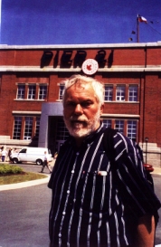 Man with grey hair and beard, standing outside the Pier21 Museum.