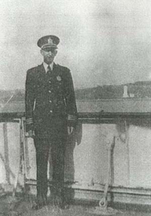 Man in police uniform standing with water in background.