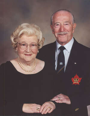 Portrait of older Betty and Bill, Betty seated with Bill standing next to her.
