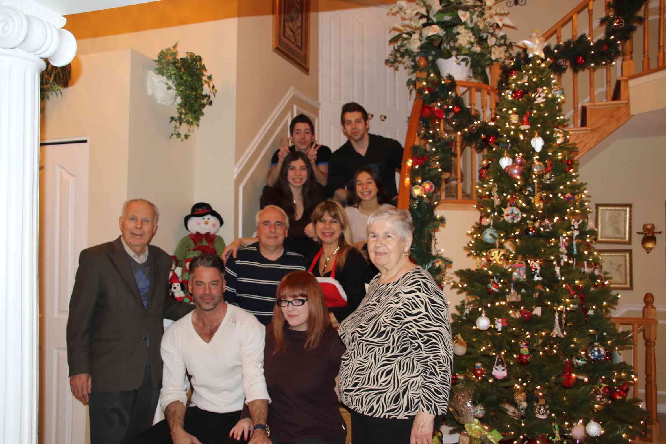 Ten people standing on stairs beside a Christmas tree.