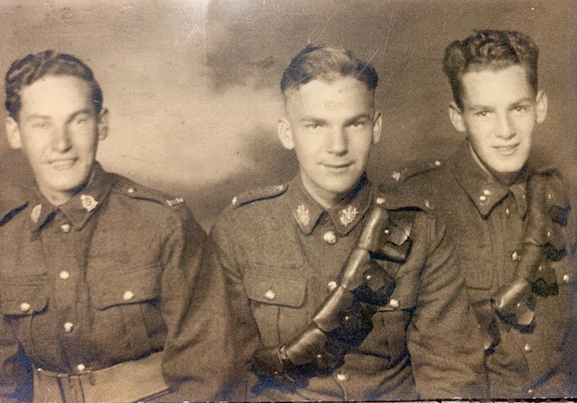 Sepia photo of three smiling white men in uniform, taken from the torso up.