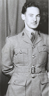 Black and white photo of a smiling white man in uniform. 